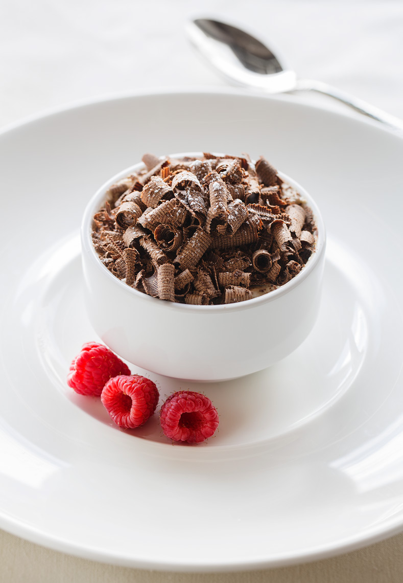 Chocolate dessert with raspberry on white bowl and plate